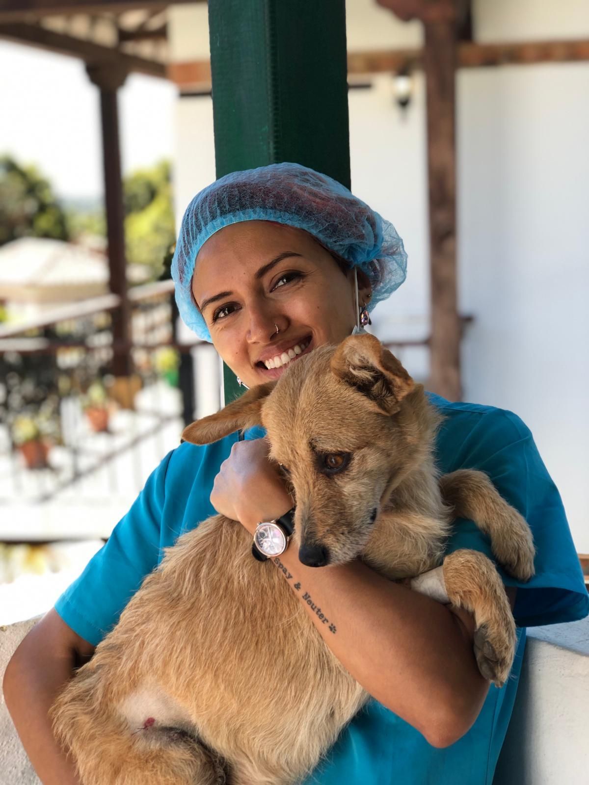 Woman wearing a surgical cap and carrying a dog